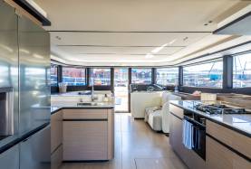 Moorings 534PC saloon and galley with a cooktop, sink, settee and helm station visible through wraparound hull windows.