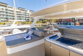 Moorings 534PC flybridge with a sunpad, cockpit settee, and a Kenyon grill station under a bimini.