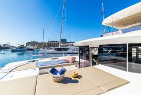 Foredeck of the Moorings 534PC catamaran, showing sunpad cushions and a companionway door to the saloon.