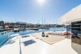 Moorings 534PC foredeck with a sunpad and stainless steel bow rail alongside a marina.