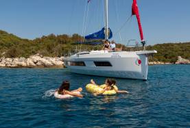 People swimming with inflatables next to sailing boat in Croatia