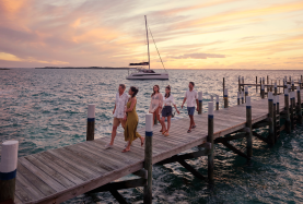 Friends walking along a dock with catamaran in the background