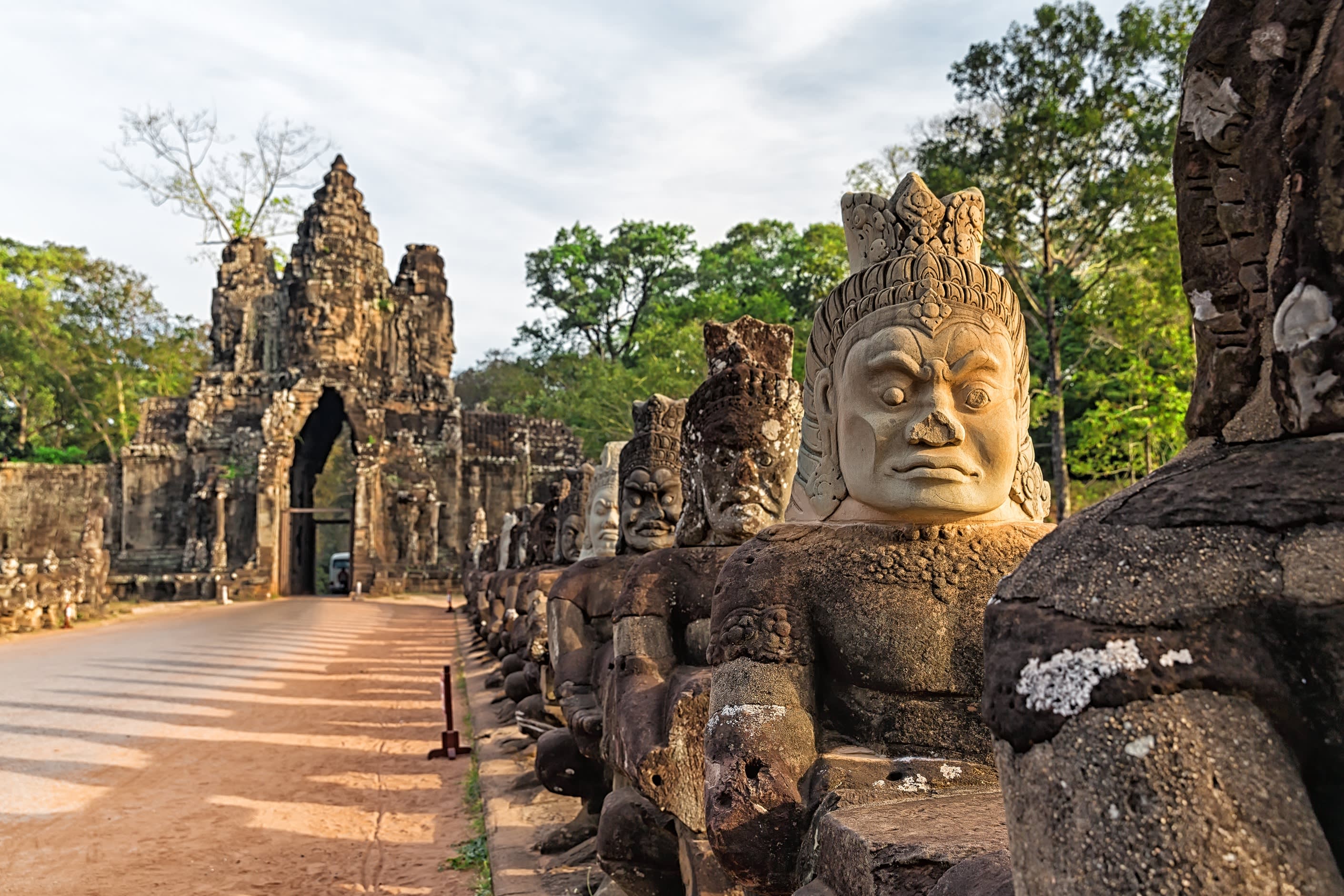 Steinerne Dämonenfiguren flankieren den Zugang zum Eingang von Angkor Thom in Kambodscha