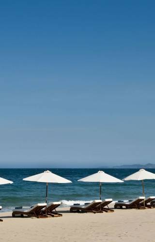 a group of lawn chairs sitting on top of a sandy beach