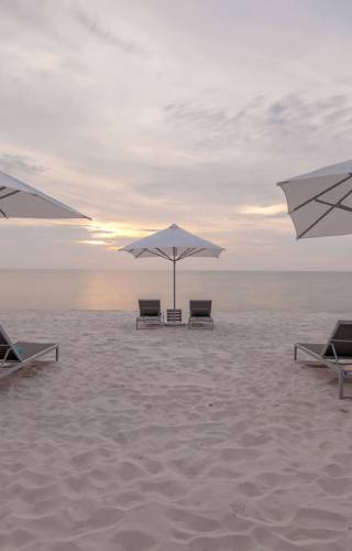 a couple of lawn chairs sitting on top of a sandy beach