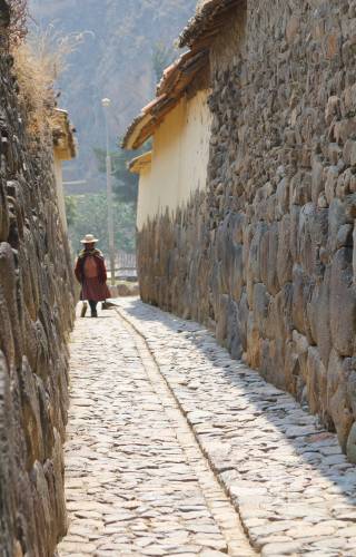a person walking down a sidewalk next to a stone wall