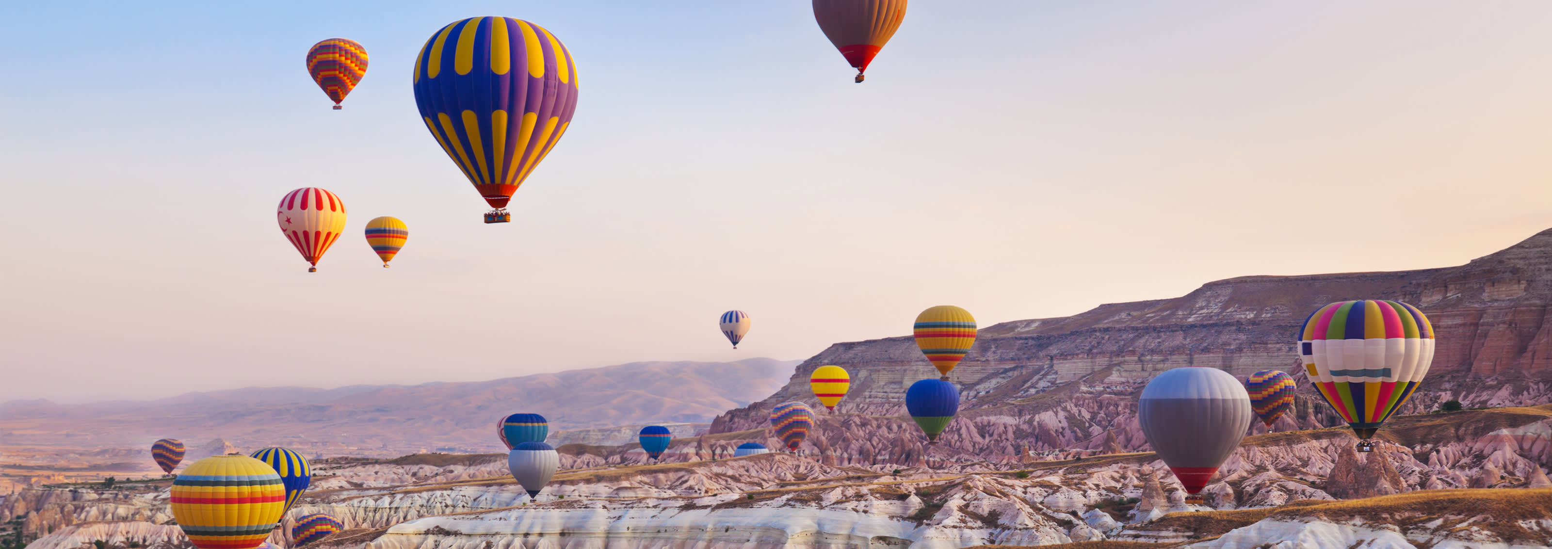 Hot air balloon flying over rock landscape at Cappadocia, Turkey