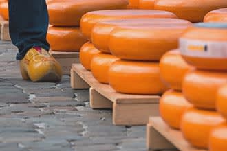 Forme di Gouda impilate in un mercato di formaggi