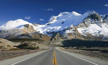 a snow covered road with a mountain in the background