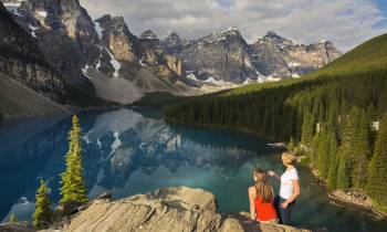 Two women standing in front of a lake with a backdrop of beautiful mountains