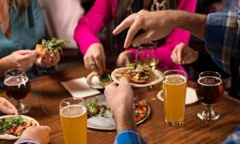 a woman sitting at a table with food and drinks