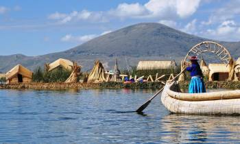 a small boat in a body of water with Lake Titicaca in the background