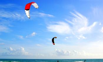 a group of people flying kites in a body of water