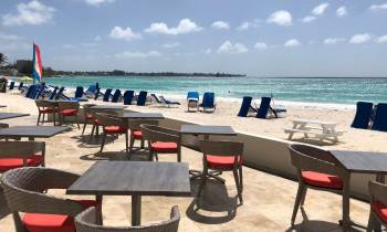 a group of lawn chairs sitting on top of a sandy beach