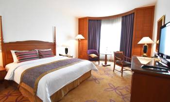 a bedroom with a bed and desk in a hotel room