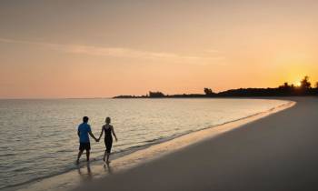 a person walking across a beach next to a body of water