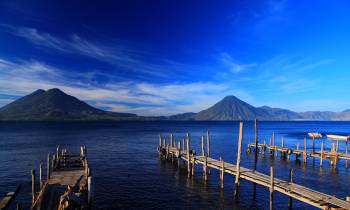 a wooden pier next to a body of water with Lake Atitlán in the background