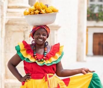 Farbenfroh gekleidete Palenquera Verkäuferin in der Altstadt von Cartagena de Indias, Kolumbien