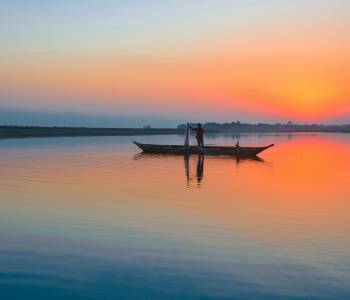 Enchanting Travels India Tours fisherman with his net and boat on the River Brahmaputra at Sunset