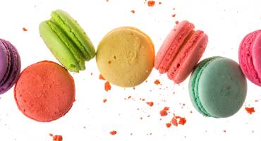 Enchanting Travels France Tours French macaroons isolated on white background. Cookies falls mixed with crumbs