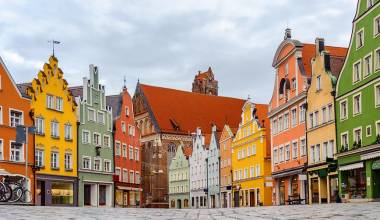 Enchanting Travels Traditional colorful gothic houses in the Old Town of Landshut, historical town in Bavaria by Munich, Germany, reflecting in a rain puddle