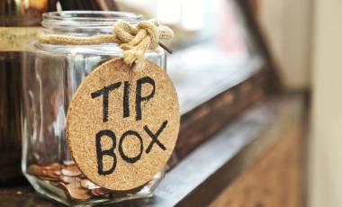 Vintage retro glass jar with hemp rope tie tip box tag and few coins inside on wood counter