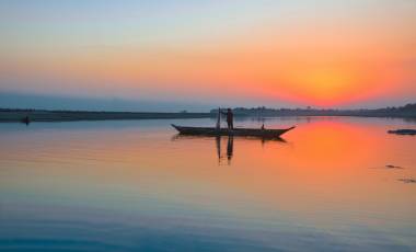 Enchanting Travels India Tours fisherman with his net and boat on the River Brahmaputra at Sunset