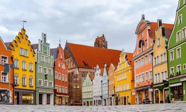 Enchanting Travels Traditional colorful gothic houses in the Old Town of Landshut, historical town in Bavaria by Munich, Germany, reflecting in a rain puddle