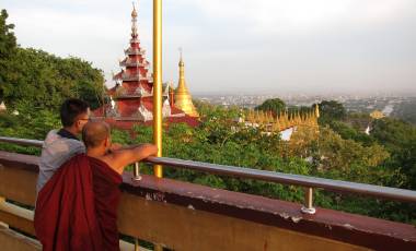 monk and boy at mandalay hill watching view on the city mandalay with golden pagoda in the background