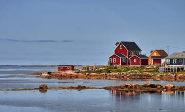 Aufnahme mehrerer roter Holzhäuser an einer Bucht auf Fogo Island, Neufundland und Labrador, Kanada