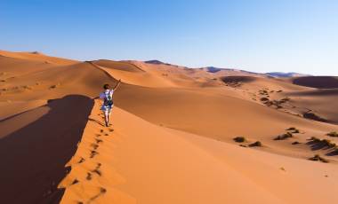 Tourist walking on the scenic dunes of Sossusvlei, Namib desert, Namib Naukluft National Park, Namibia.