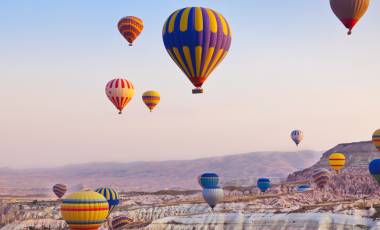 Hot air balloon flying over rock landscape at Cappadocia, Turkey