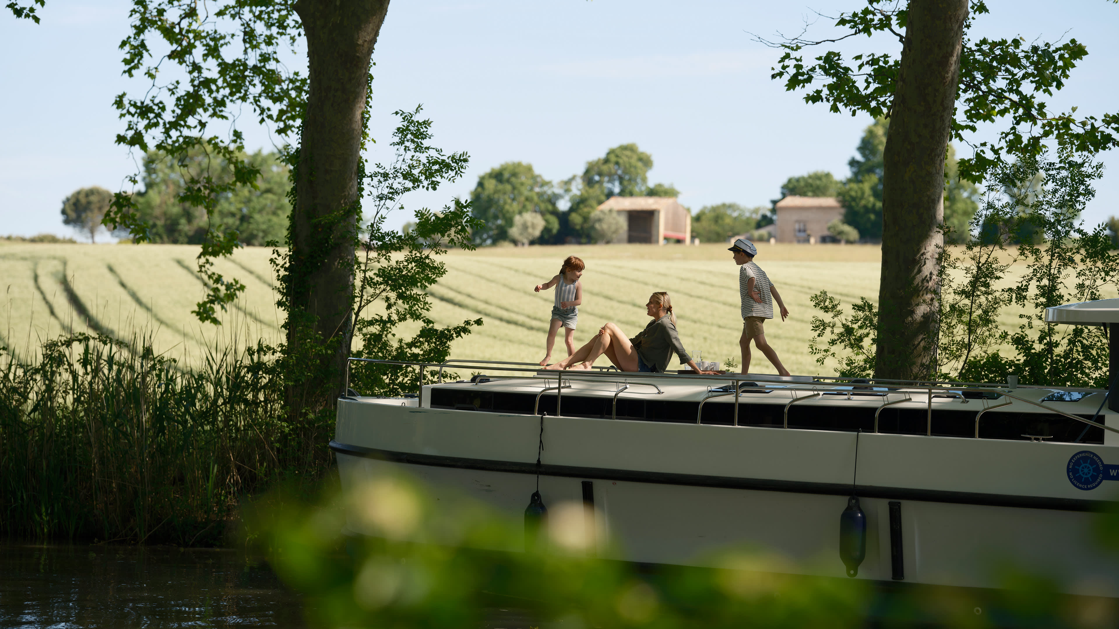 Due bambini giocano mentre la loro mamma si rilassa sulla barca, godendosi una giornata di sole.