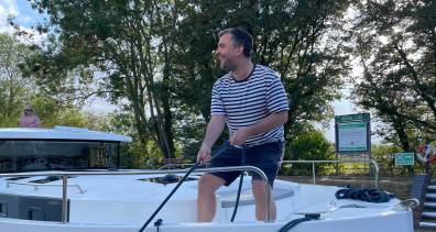 Man handling a rope on the Horizon boat’s deck while preparing to moor at a lock.