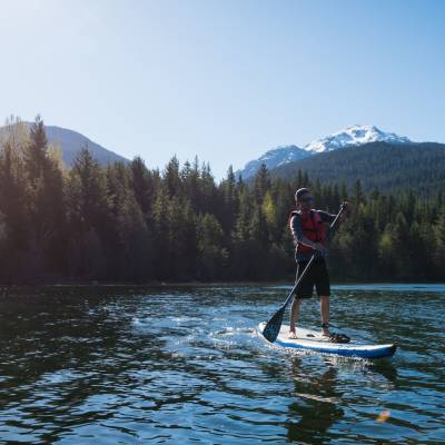 a man standing in front of a lake with a mountain in the background