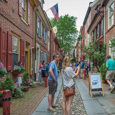 a group of people walking on a sidewalk with Beacon Hill in the background