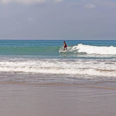 a man walking across a beach next to the ocean