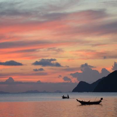 a sunset over a body of water with a mountain in the background
