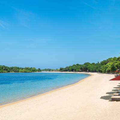 a row of lawn chairs sitting on top of a sandy beach