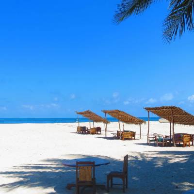 a couple of lawn chairs sitting on top of a sandy beach
