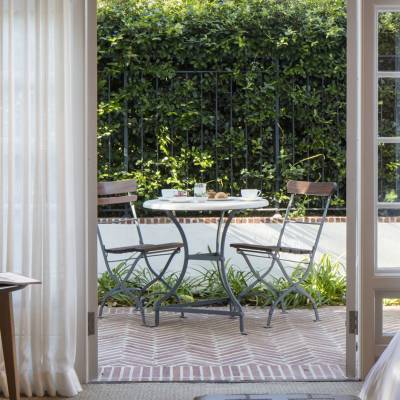 a room filled with furniture and vase of flowers on a sunny window