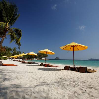 a group of lawn chairs sitting on top of a sandy beach
