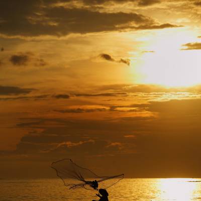 a sunset behind a boat on a body of water