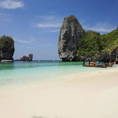 a group of people on a beach near a body of water with Railay Beach in the background