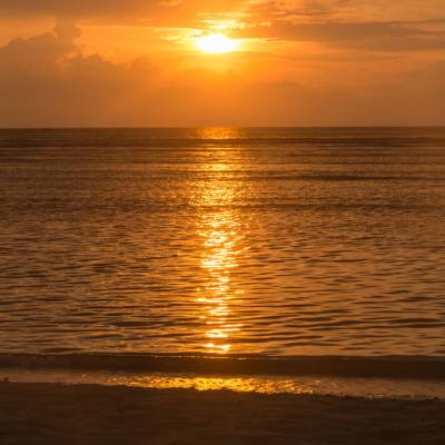 a sunset over a beach next to the ocean