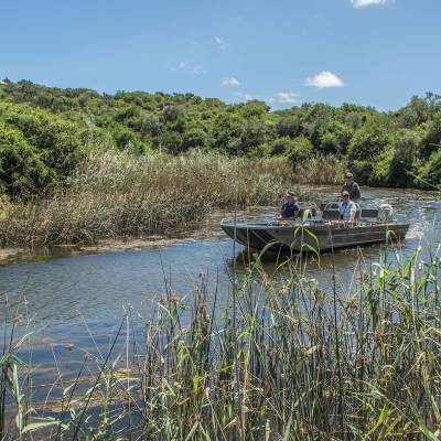 a boat floating along a river next to a body of water