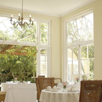 a room filled with furniture and vase of flowers on a sunny window