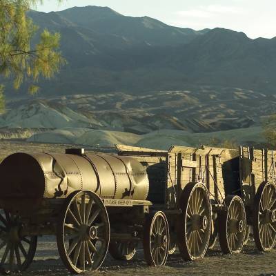 a close up of a horse drawn carriage in front of a mountain