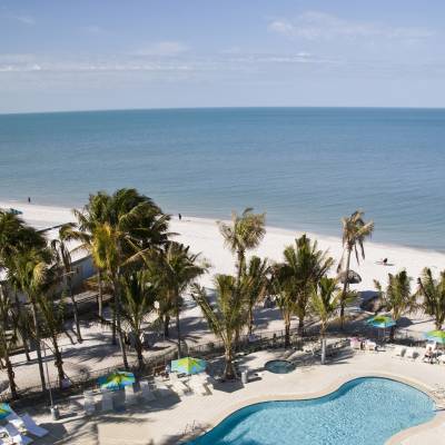 a group of people at a beach umbrella next to a body of water