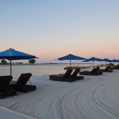 a group of lawn chairs sitting on top of a sandy beach